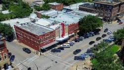 Aerial view of Texas Theater in a historic neighborhood with surrounding parked cars and buildings.