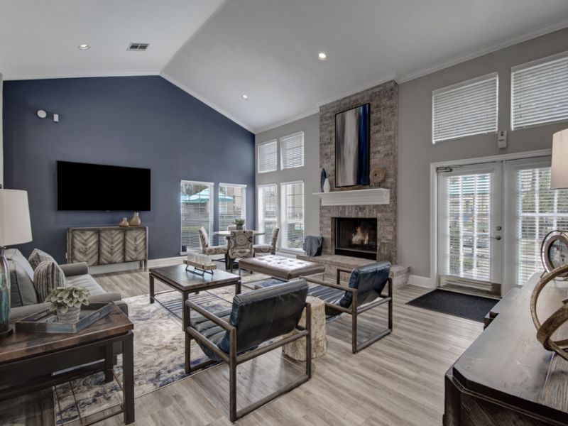 Modern living room with high ceiling, dark accent wall, fireplace, large windows, and stylish furniture.