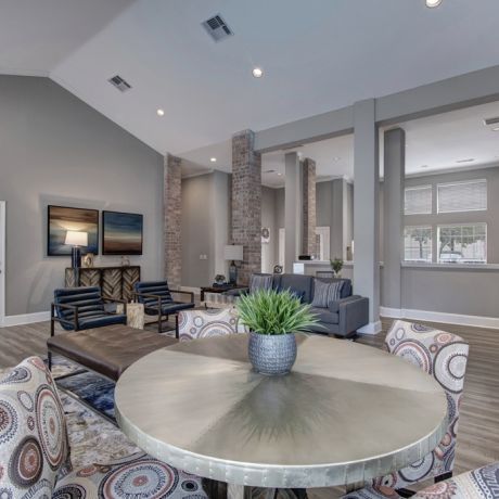 Spacious living area with modern furniture, a round table, patterned chairs, and wall-mounted TV.