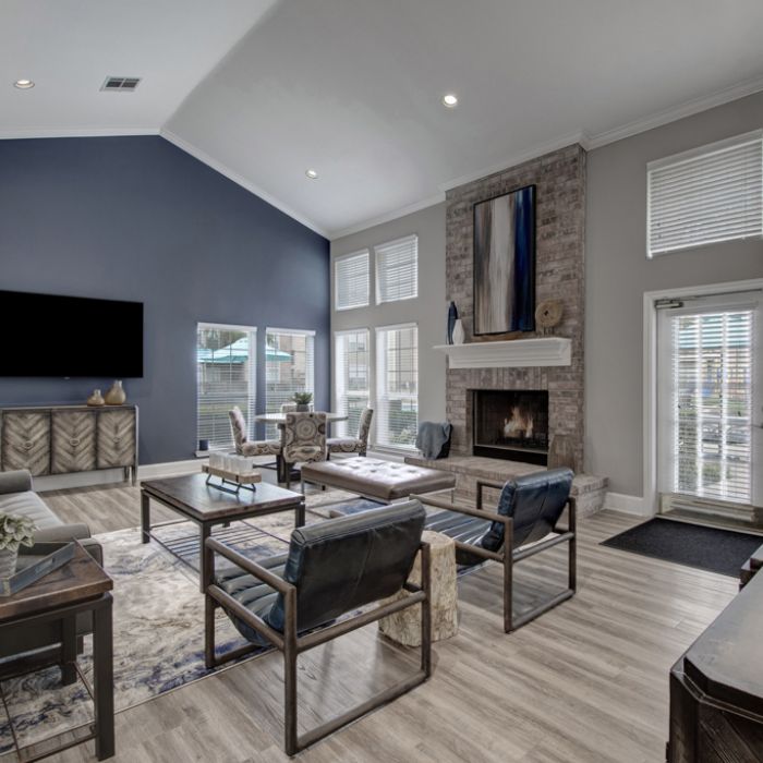 Modern living room with high ceiling, dark accent wall, fireplace, large windows, and stylish furniture.